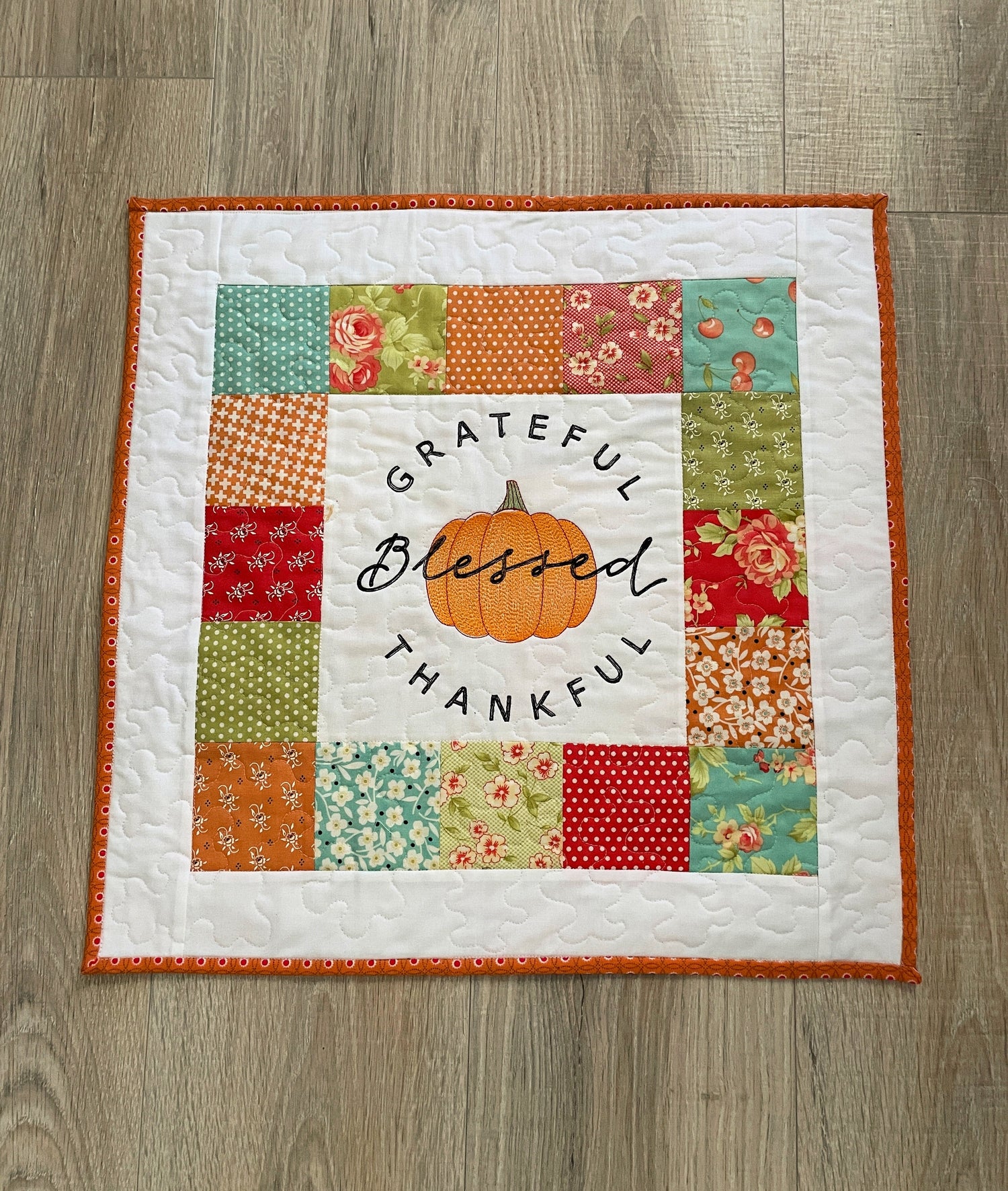 Quilted Fall patchwork mini quilt with embroidered pumpkin in the center and text Grateful, Blessed, Thankful