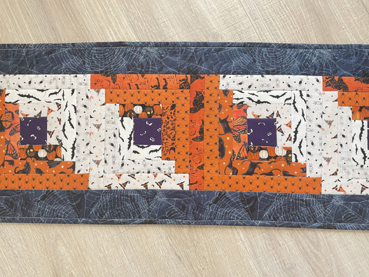 Scrappy Halloween quilted table runner with pumpkins, cats, and witchy prints