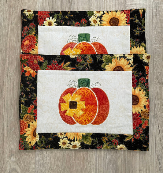 set of 4 handmade quilted placemats for fall with machine embroidered pumpkin and sunflower in the center.