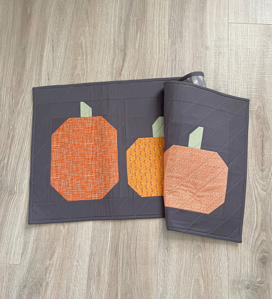 quilted table runner for fall, orange pumpkins on a gray background
