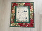 Handmade quilted Christmas wall hanging with an “Away in a Manger” verse framed by red poinsettias.
