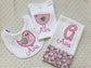 A personalized 3-piece baby girl gift set featuring a pink bird bodysuit, a white chenille bib, and a monogrammed burp cloth.