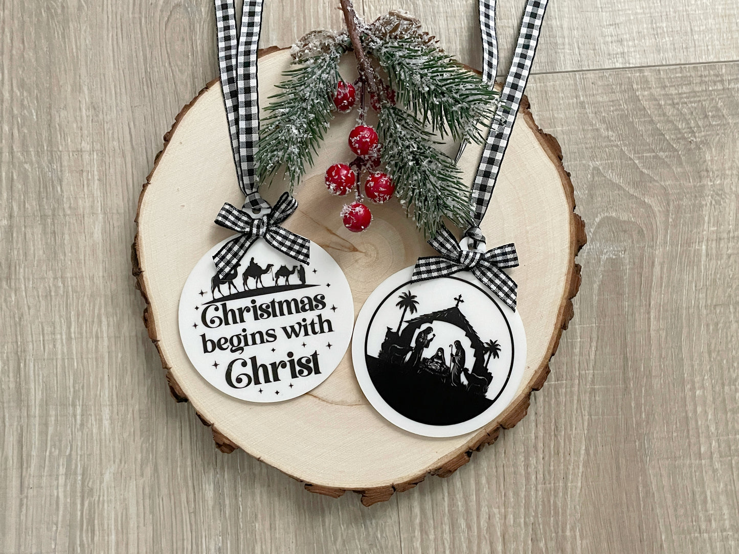 “Two acrylic Christian Christmas ornaments with gingham ribbon bows featuring ‘Christmas Begins with Christ’ and a nativity manger scene.”