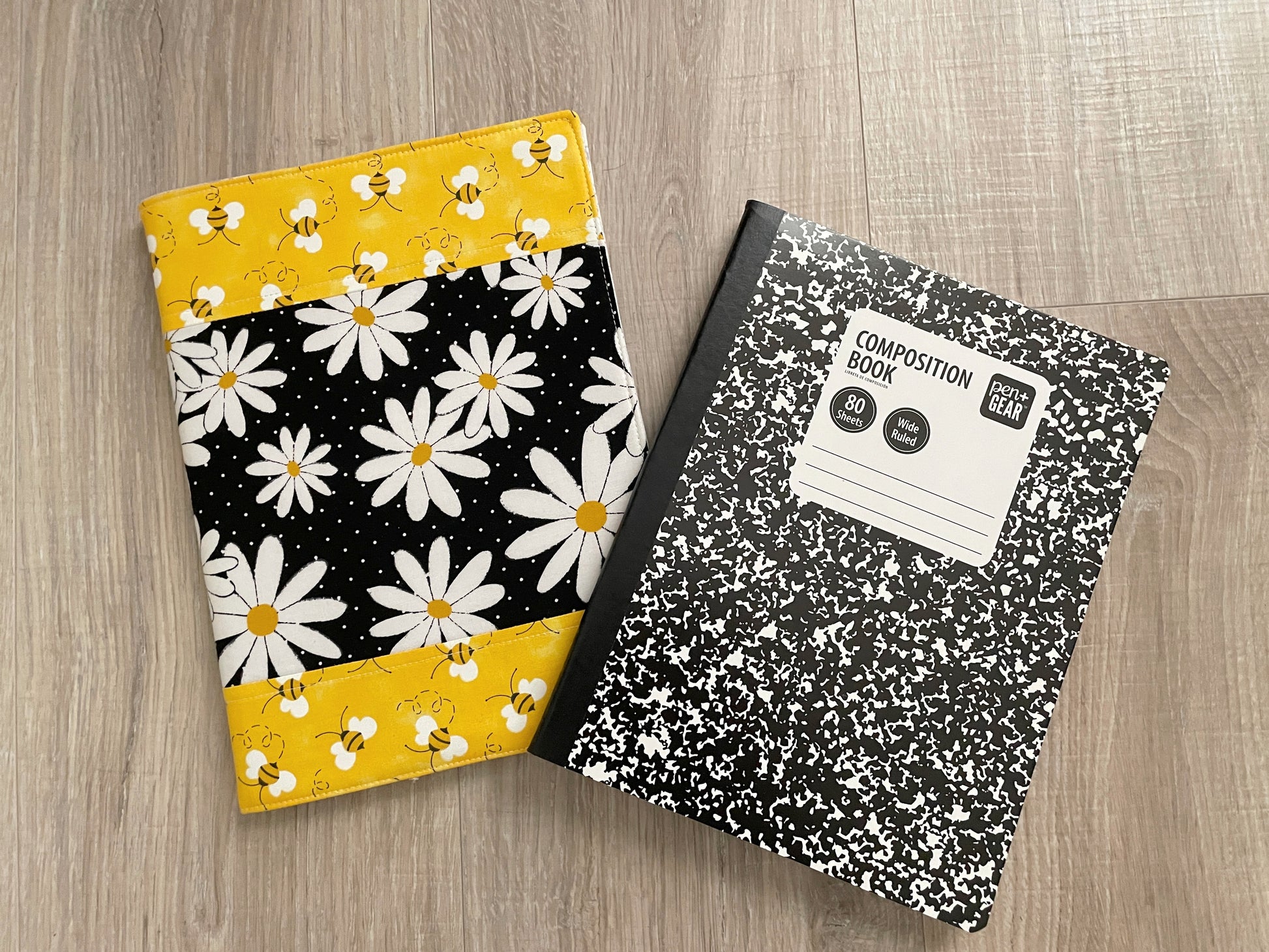 Handmade daisy‑and‑bee quilted notebook cover in black, white, and yellow fabric