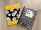 Handmade daisy‑and‑bee quilted notebook cover in black, white, and yellow fabric