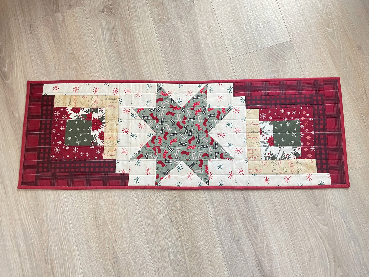 Quilted Christmas table runner with Log Cabin and Star blocks in red, white, and green
