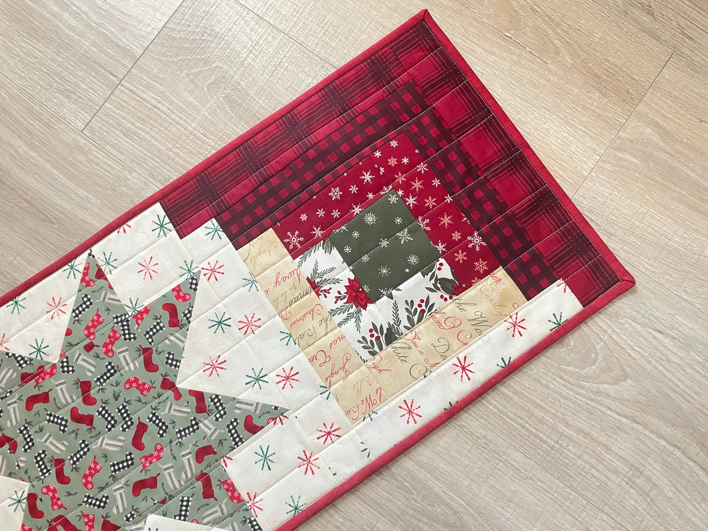 Quilted Christmas table runner with Log Cabin and Star blocks in red, white, and green
