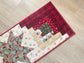 Quilted Christmas table runner with Log Cabin and Star blocks in red, white, and green