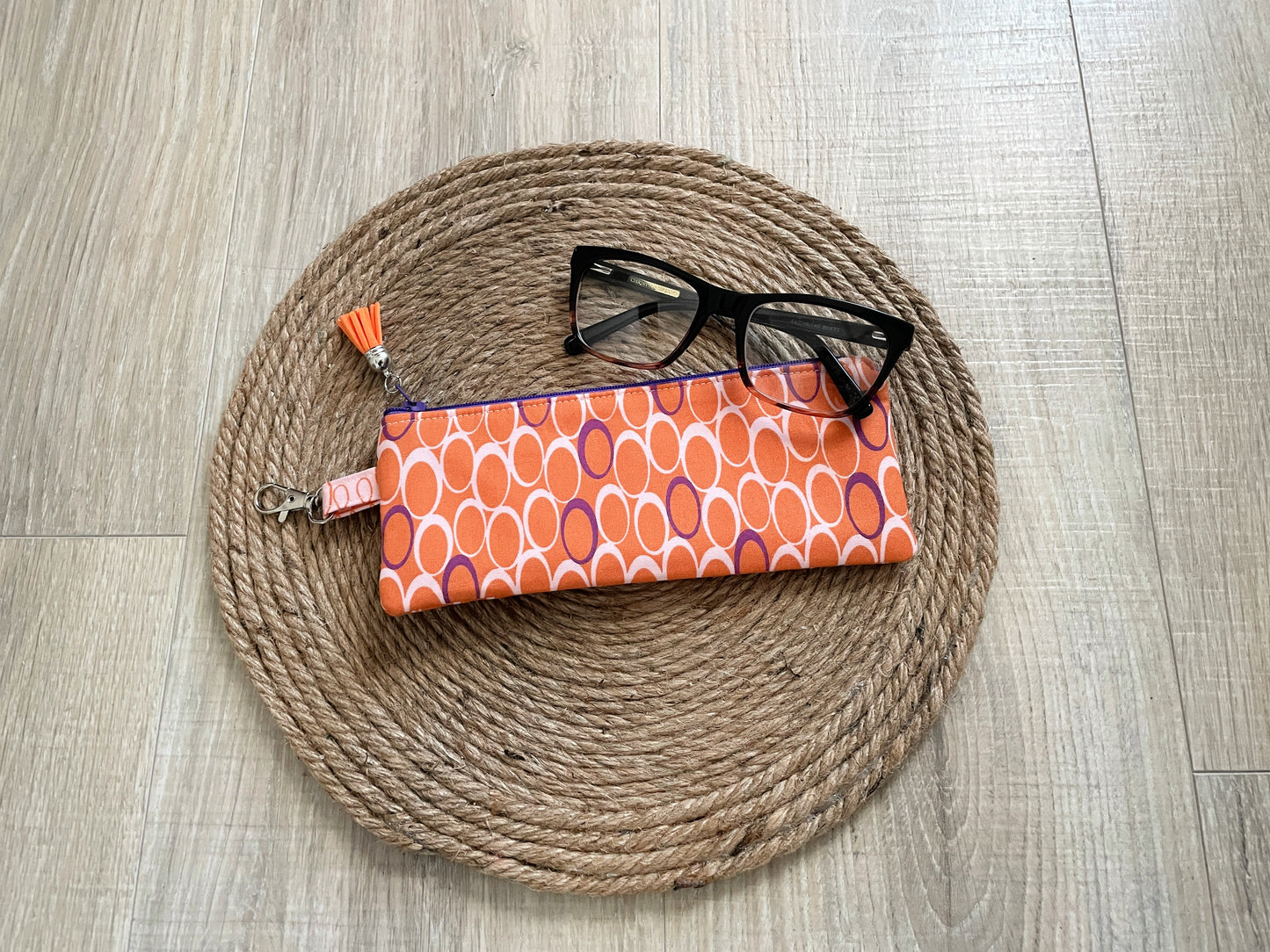 Pink, purple and orange retro dot print eyewear case with zipper and leather tassel.”