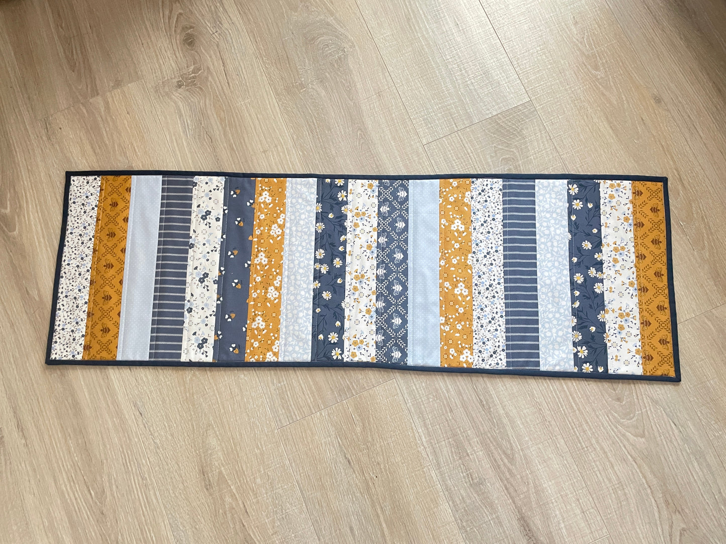 Quilted table runner with floral and bee prints in blues and golds