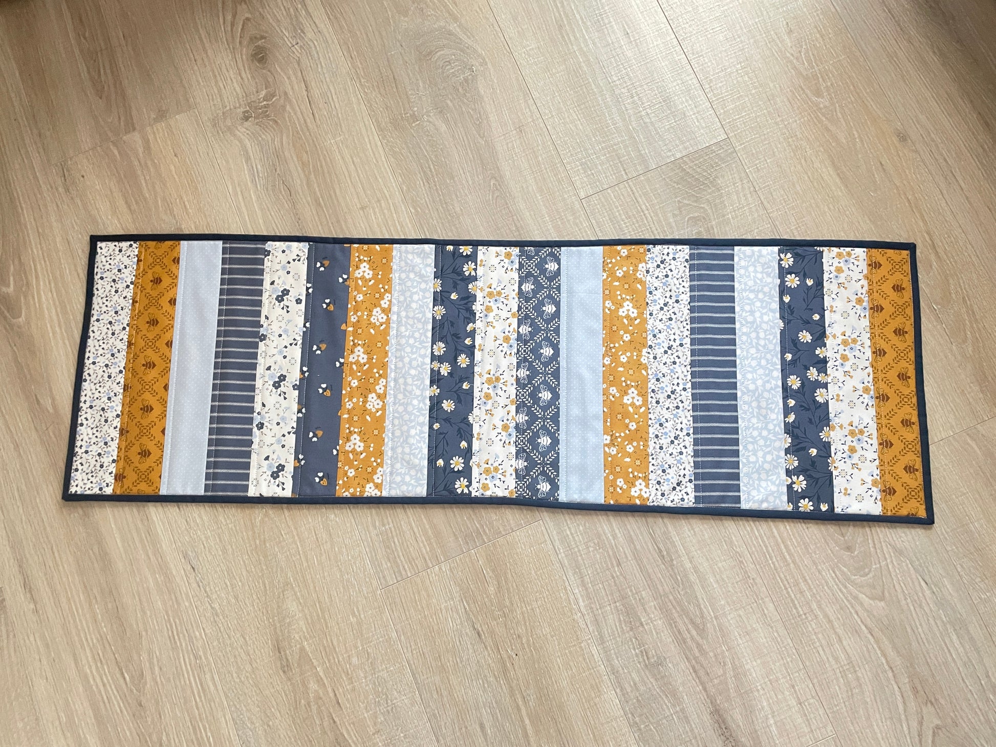 Quilted table runner with floral and bee prints in blues and golds