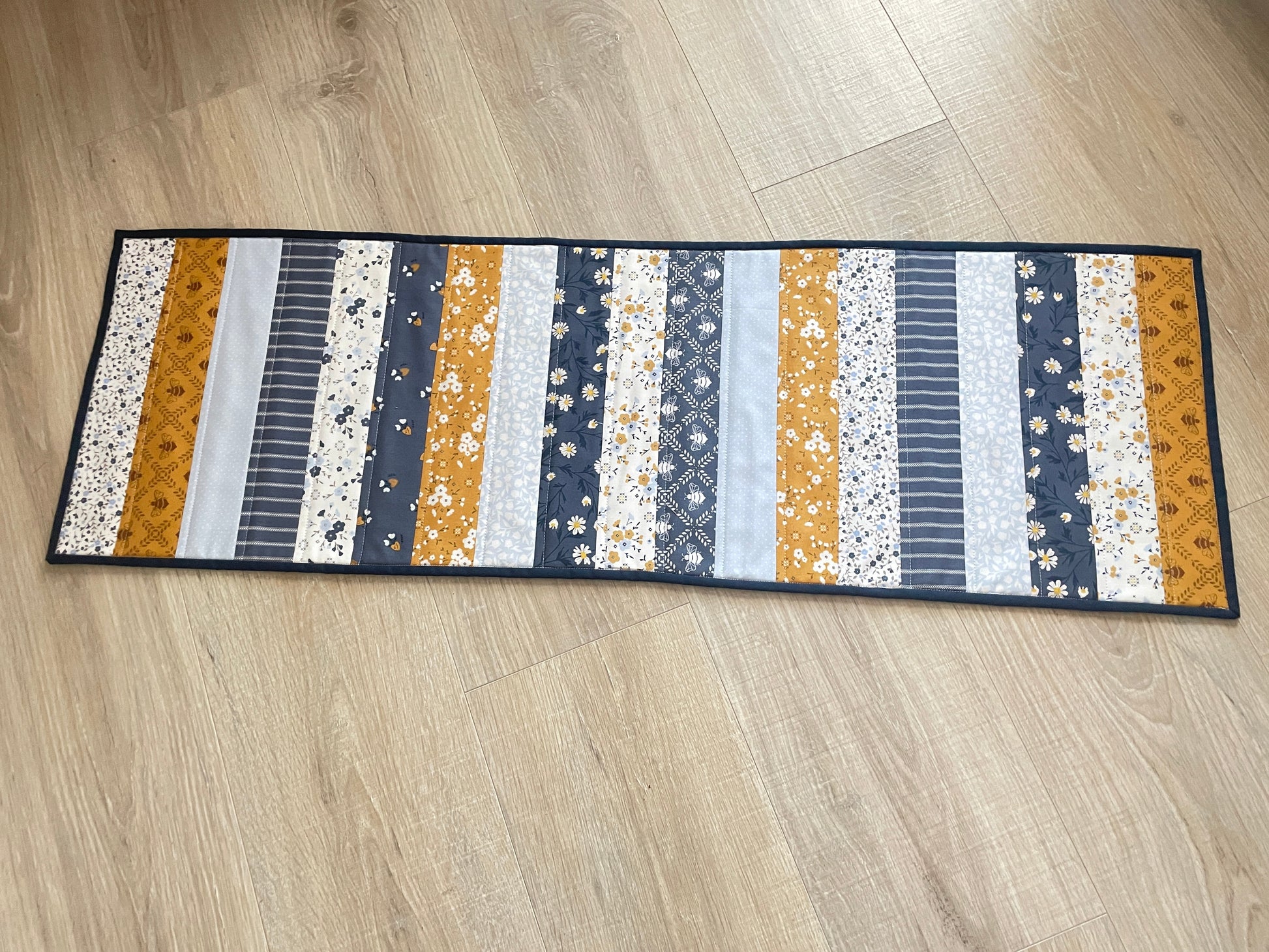 Quilted table runner with floral and bee prints in blues and golds