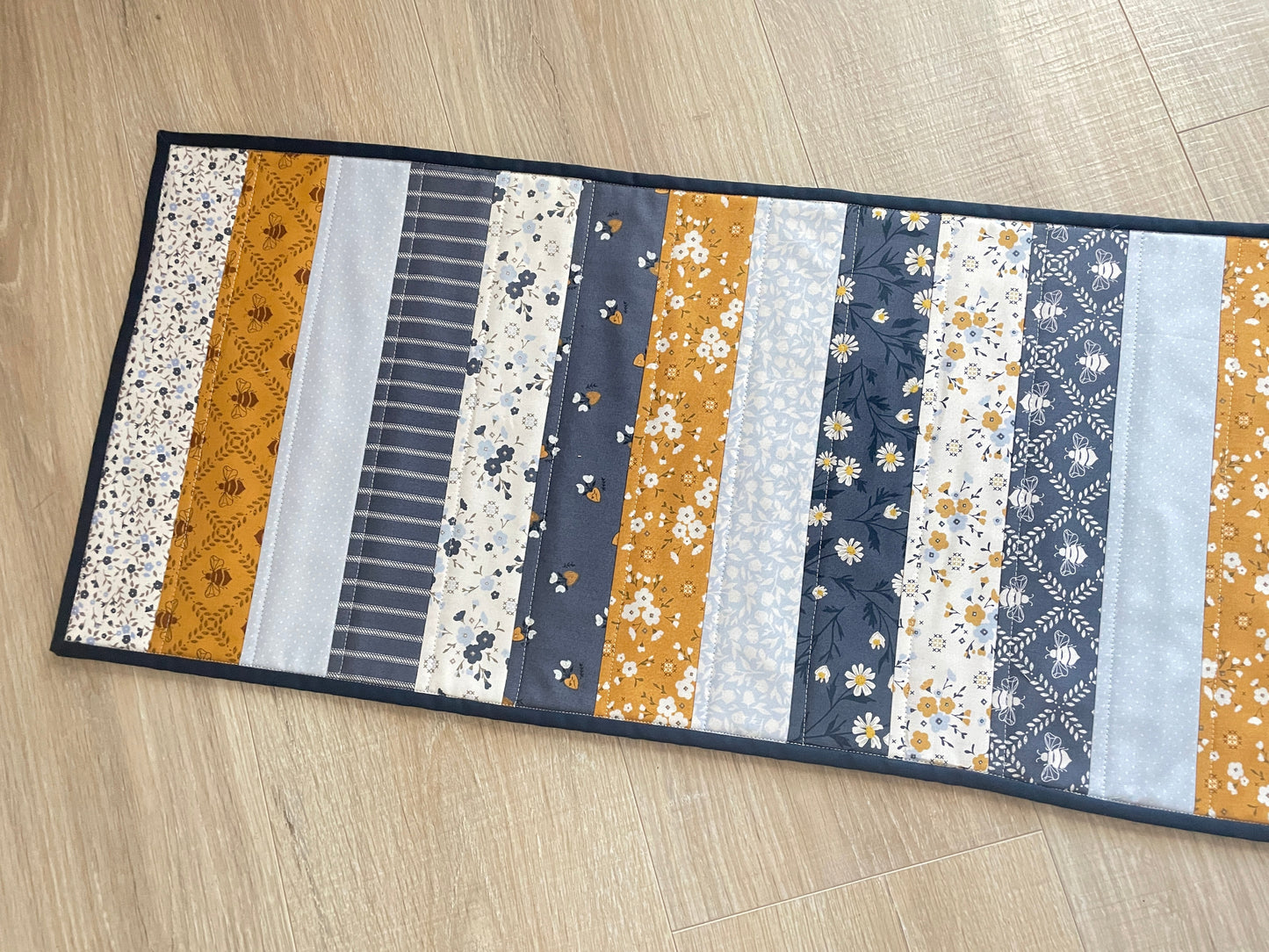 Quilted table runner with floral and bee prints in blues and golds