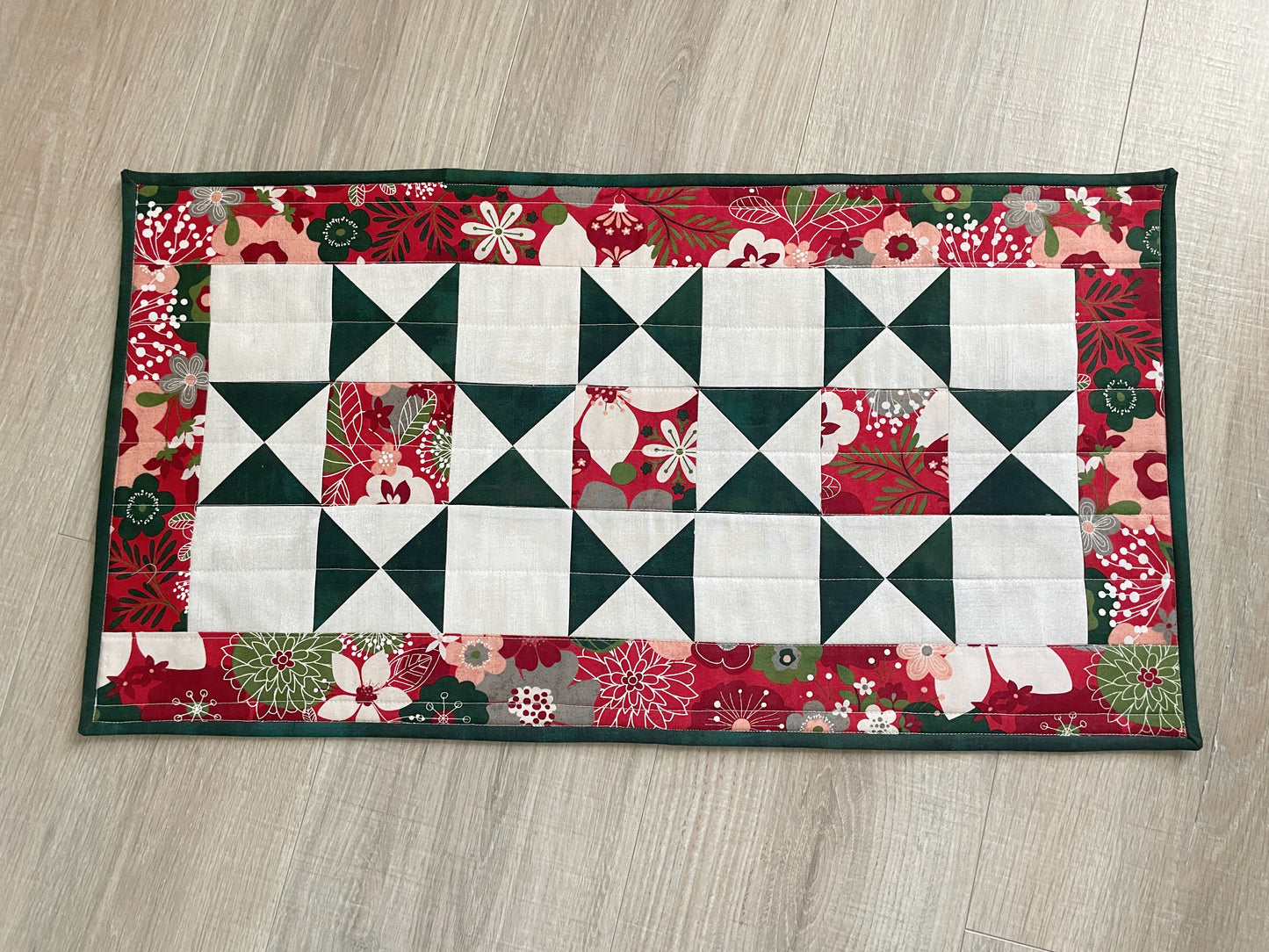 Handmade quilted Christmas table runner in red and green Hustle & Bustle fabric by Basic Grey, 13x26 inches.