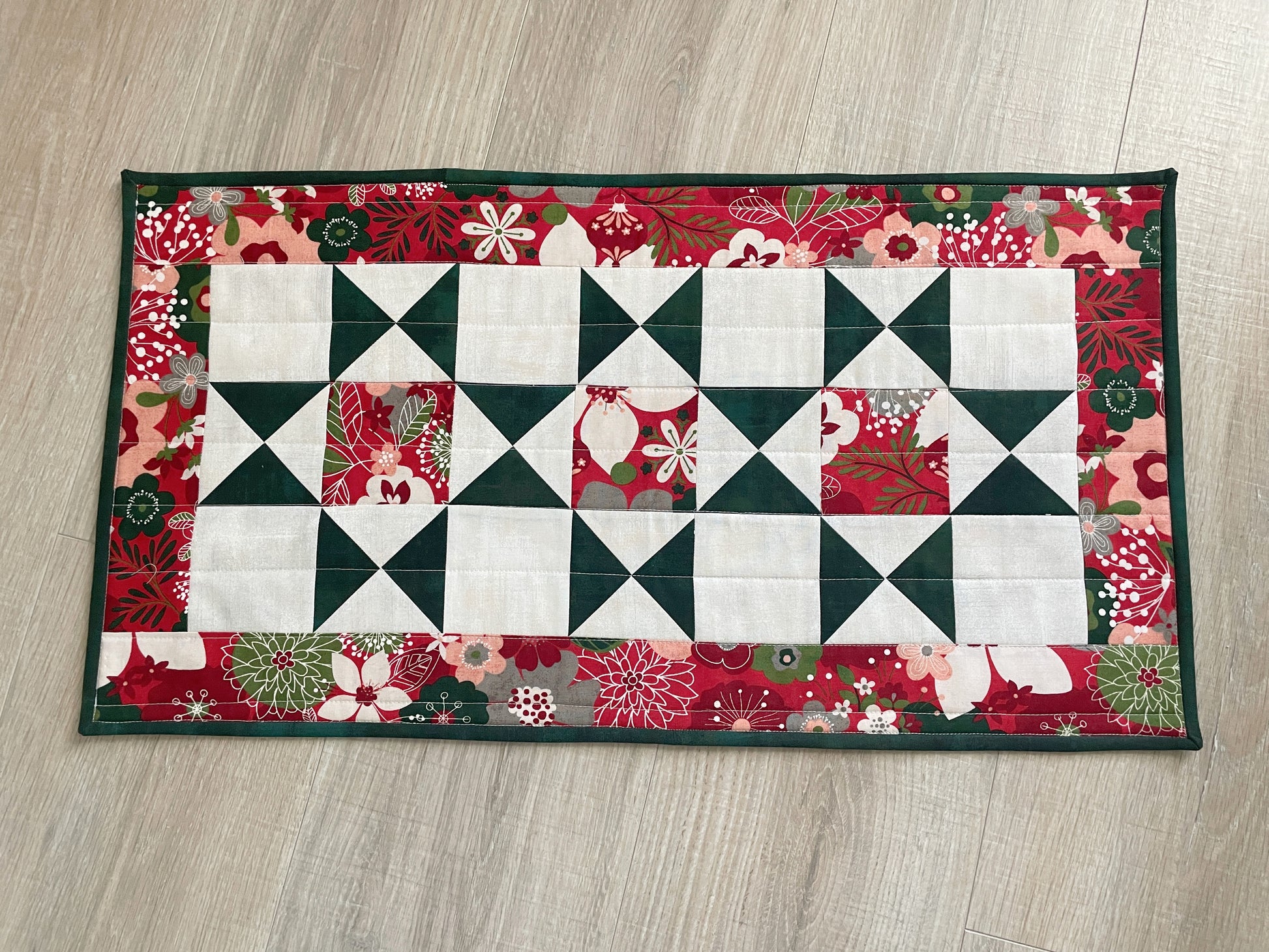 Handmade quilted Christmas table runner in red and green Hustle & Bustle fabric by Basic Grey, 13x26 inches.