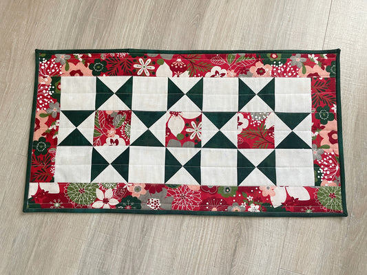 Handmade quilted Christmas table runner in red and green Hustle & Bustle fabric by Basic Grey, 13x26 inches.