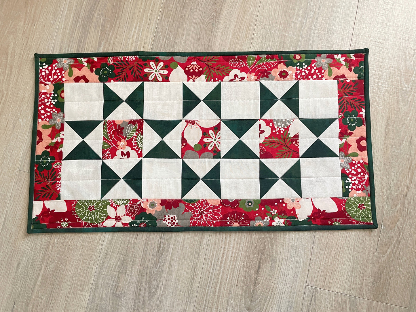 Handmade quilted Christmas table runner in red and green Hustle & Bustle fabric by Basic Grey, 13x26 inches.
