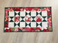 Handmade quilted Christmas table runner in red and green Hustle & Bustle fabric by Basic Grey, 13x26 inches.