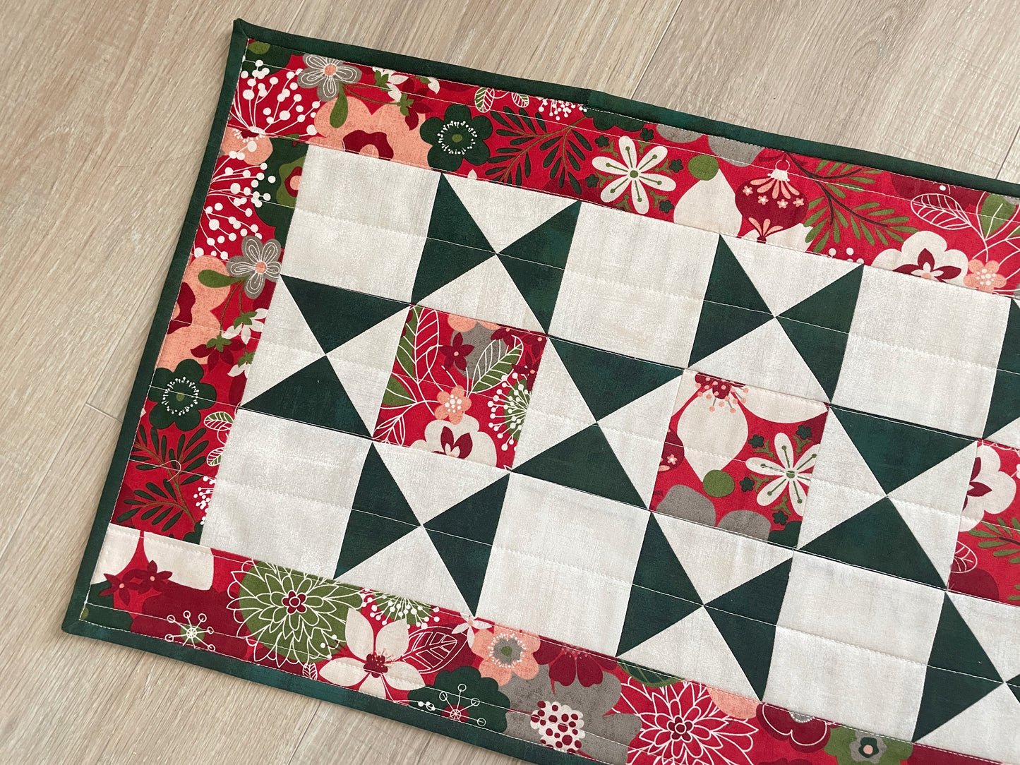 Handmade quilted Christmas table runner in red and green Hustle & Bustle fabric by Basic Grey, 13x26 inches.