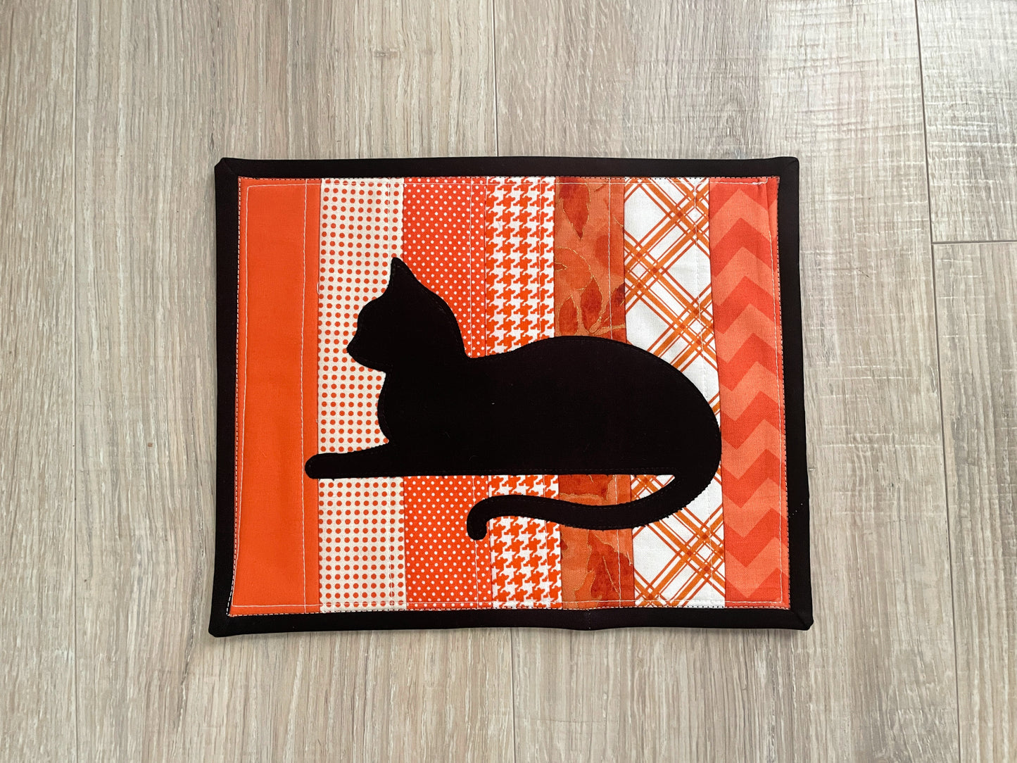 Quilted orange mug rug with black cat appliqué, handmade 8x10 snack mat.