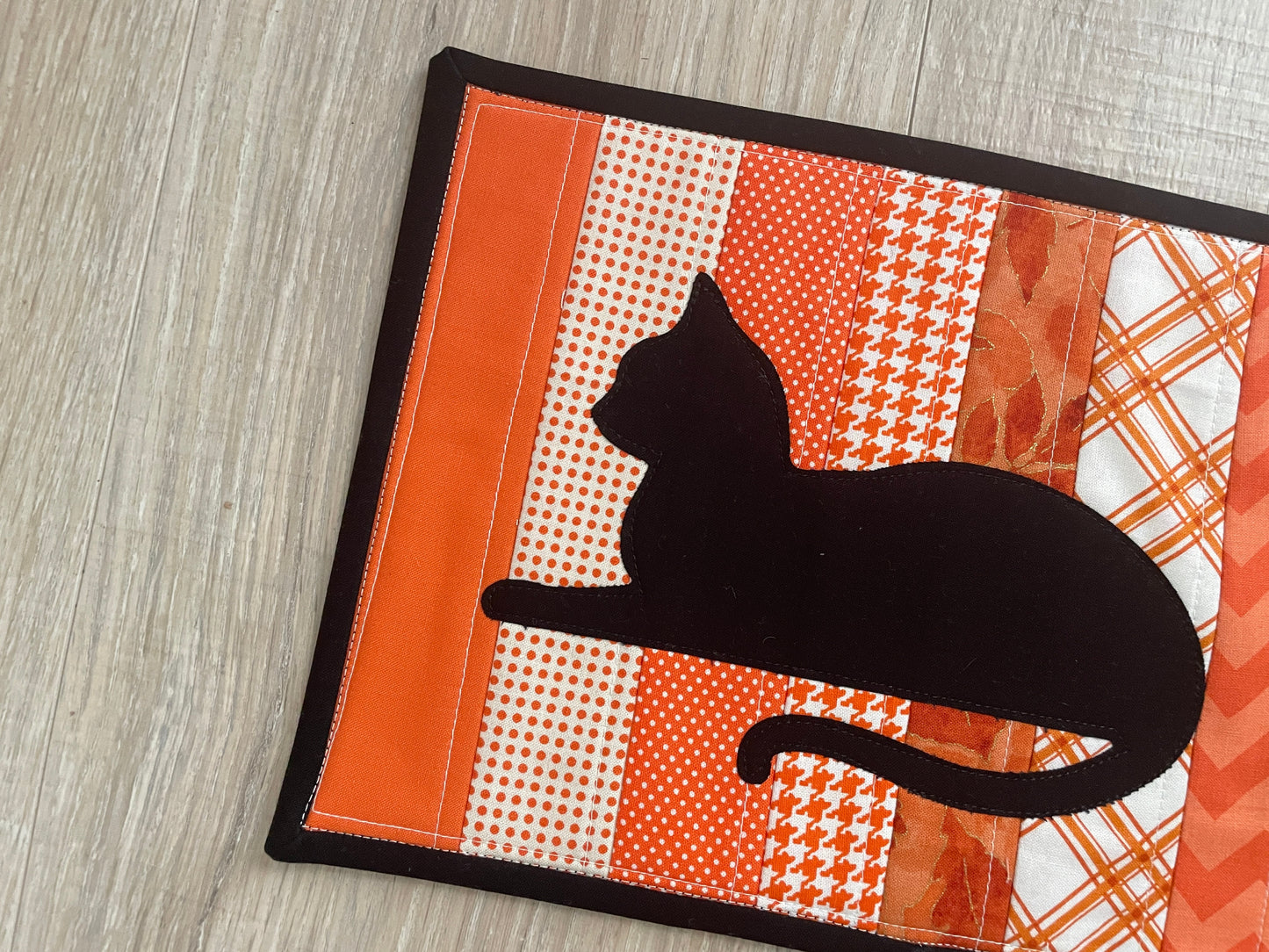 Quilted orange mug rug with black cat appliqué, handmade 8x10 snack mat.