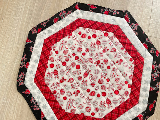 Quilted octagon Christmas table topper with red, white, black, and silver holiday fabrics