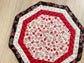 Quilted octagon Christmas table topper with red, white, black, and silver holiday fabrics