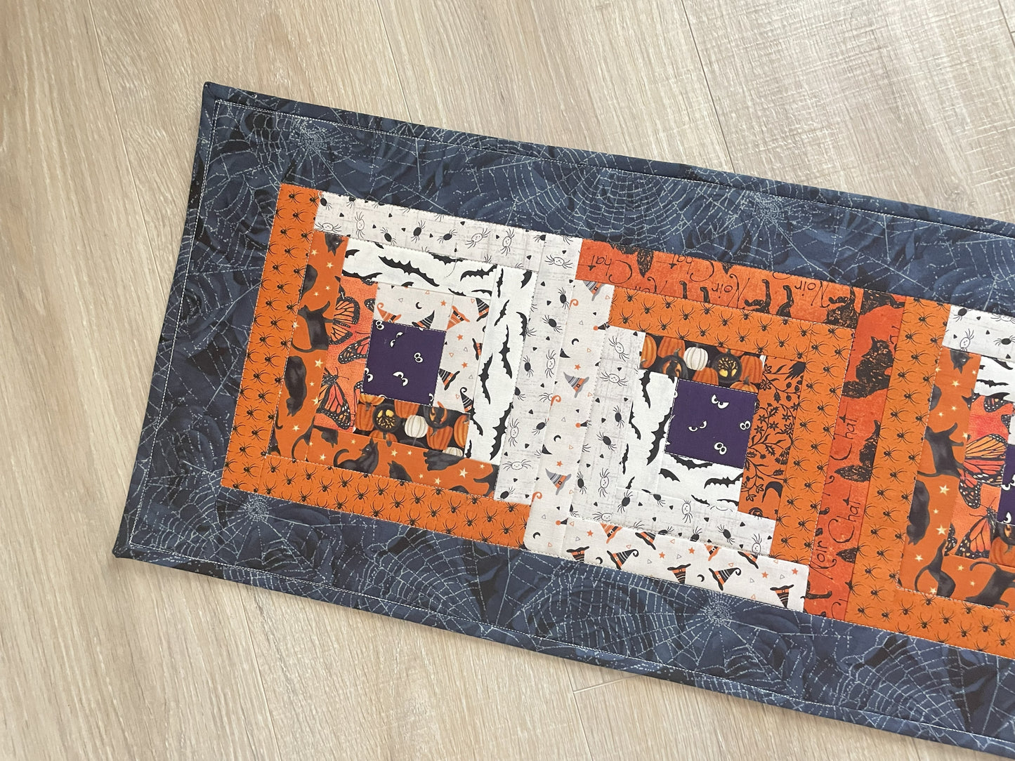 Scrappy Halloween quilted table runner with pumpkins, cats, and witchy prints