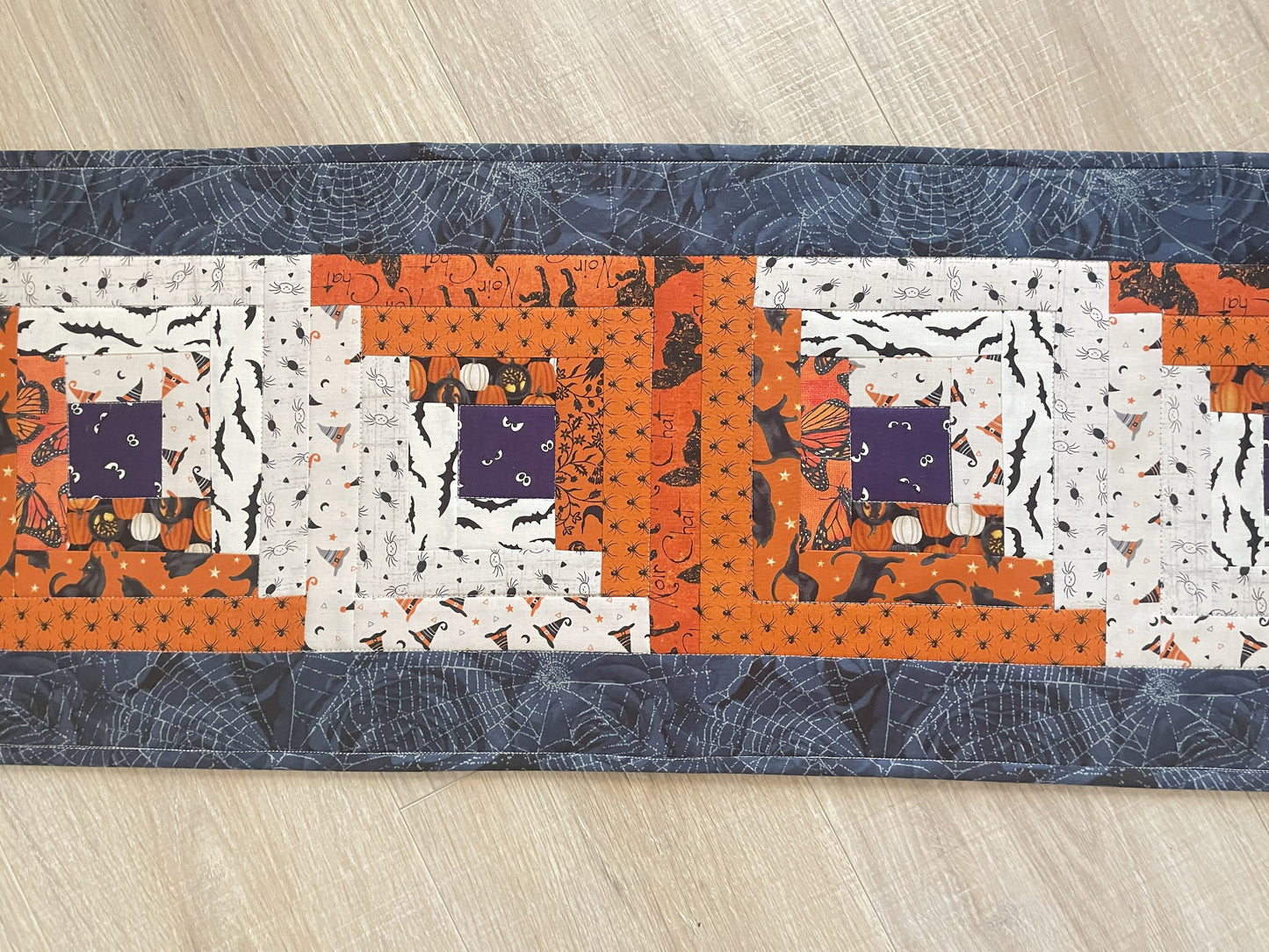 Scrappy Halloween quilted table runner with pumpkins, cats, and witchy prints