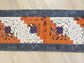 Scrappy Halloween quilted table runner with pumpkins, cats, and witchy prints