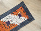 Scrappy Halloween quilted table runner with pumpkins, cats, and witchy prints