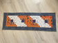 Scrappy Halloween quilted table runner with pumpkins, cats, and witchy prints