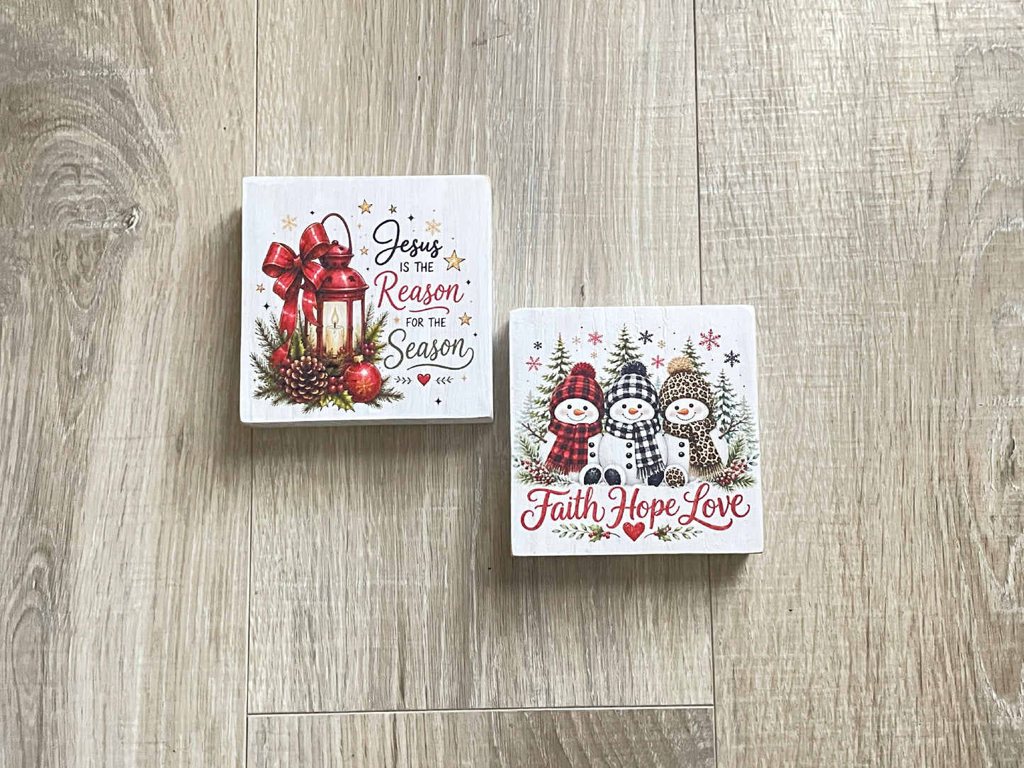 Two freestanding winter shelf sitters featuring "Jesus Is the Reason for the Season" and "Faith Hope Love" designs with snowmen and holiday accents.