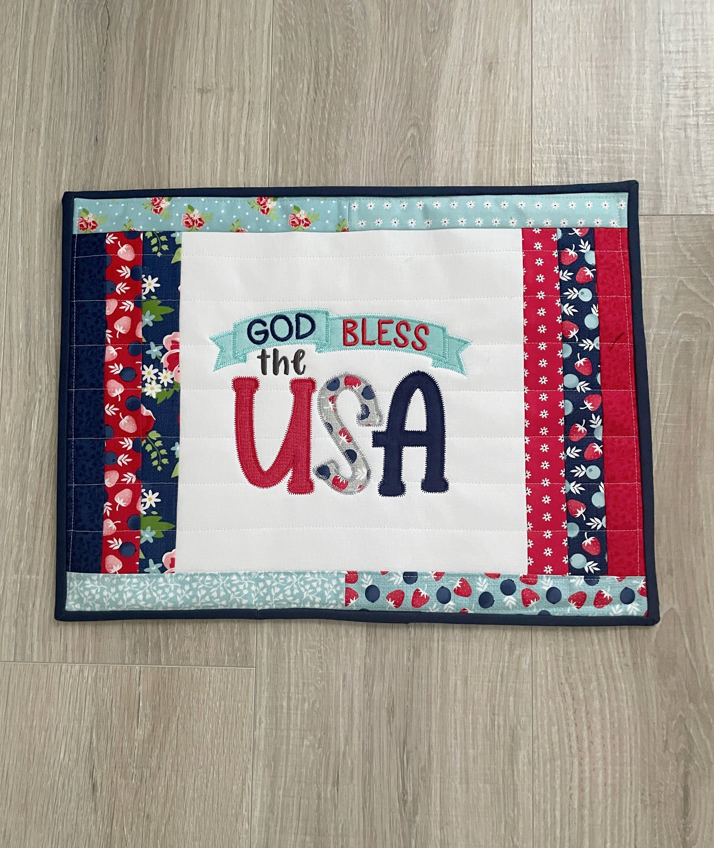 This 12 x 16 red, white, and blue quilted casserole hot pad/trivet has a scrappy patchwork center panel featuring a machine embroidered design -- God Bless the USA. These are perfect for a 9 x 13 casserole dish or 2 smaller baking dishes.