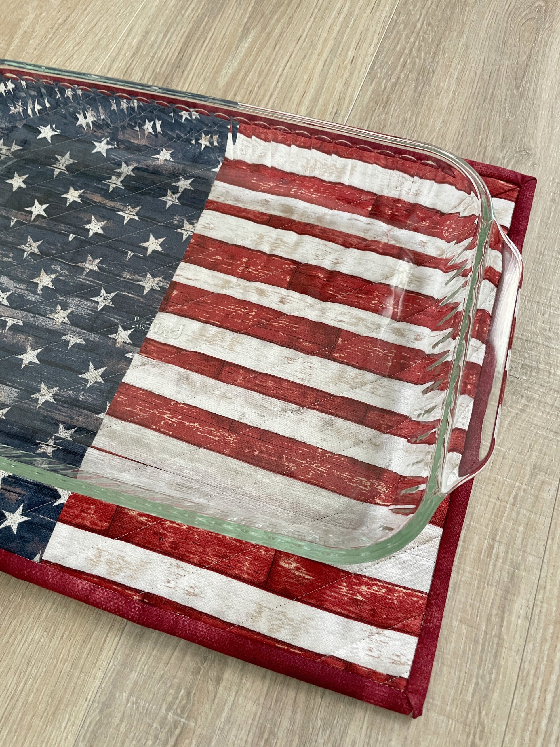 This lovely red, white, and blue quilted casserole hot pad makes your table beautiful!  Measuring 13 x 16 inches, this handmade kitchen trivet features a scrappy improv patchwork resembling the American Flag,  making it perfect for a 9 x 13 casserole dish or 2 smaller baking dishes.