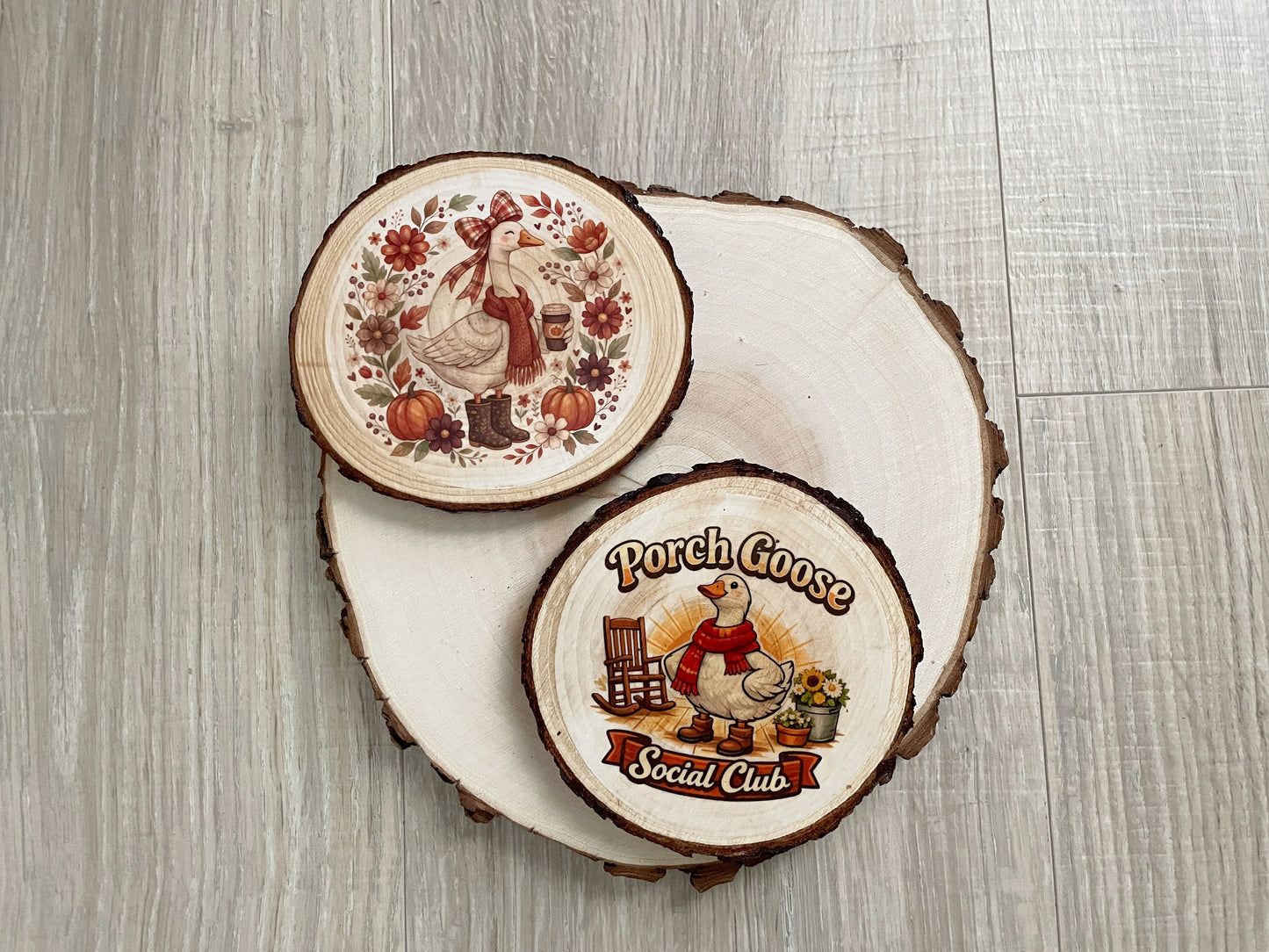 Set of two handmade rustic wood slice porch goose coasters featuring a Porch Goose Social Club emblem and an autumn pumpkin print.