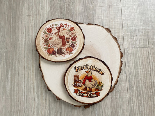 “Set of two porch goose wood slice coasters with live bark edges and printed farmhouse designs.”