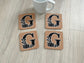 Set of four 4×4 cork coasters with monogram initial and fall pumpkin and leaf design.