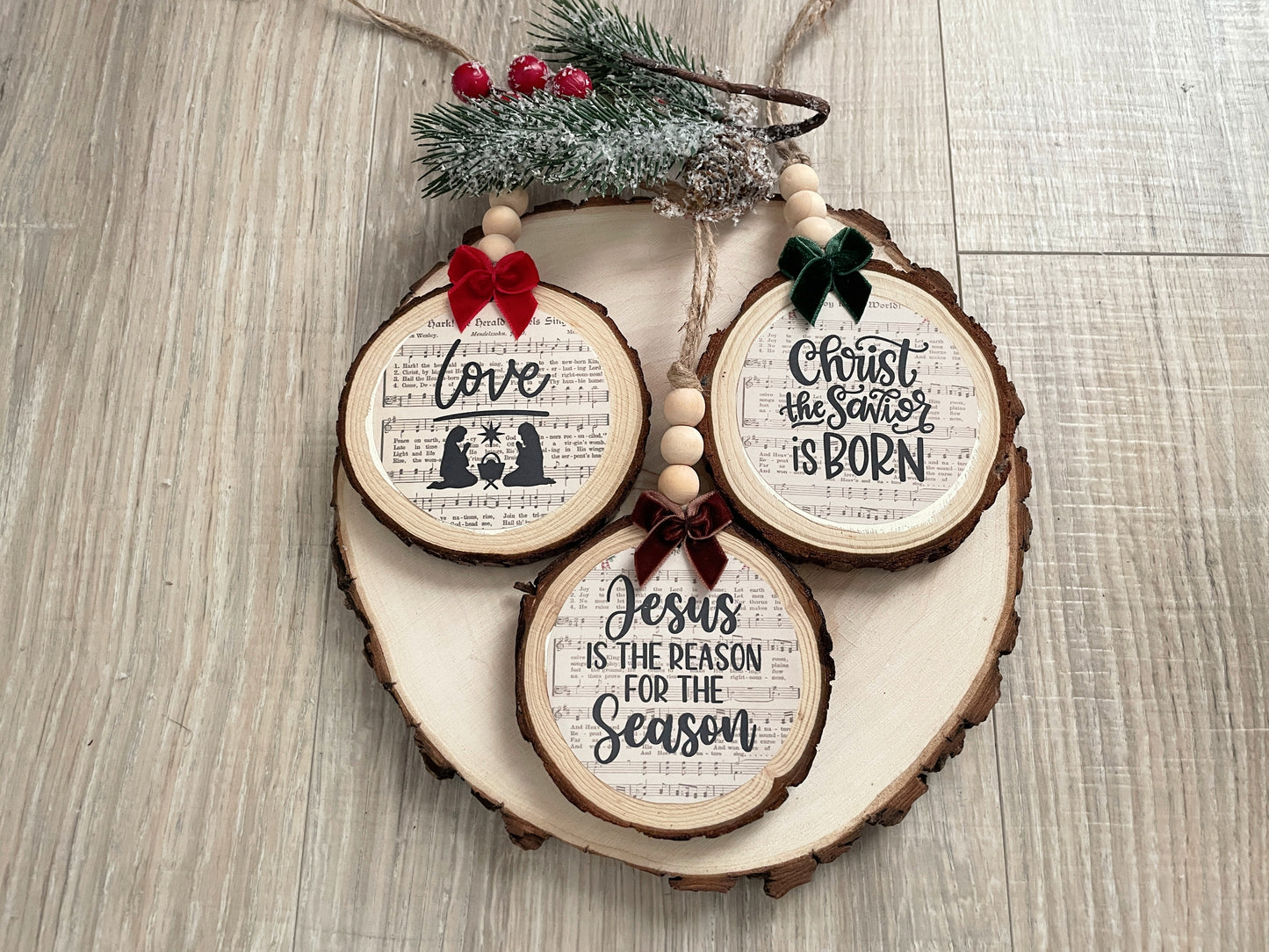 Set of three handcrafted nativity wood slice ornaments with hymn background, velvet bows,wooden beads, and jute hangers.