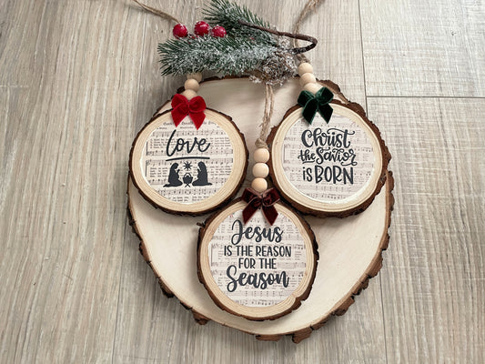 Set of three handcrafted nativity wood slice ornaments with hymn background, velvet bows,wooden beads, and jute hangers.