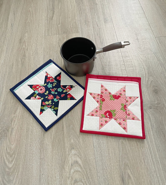 set of two pocket potholders in blue, pink and red. Star patchwork design on front pocket.