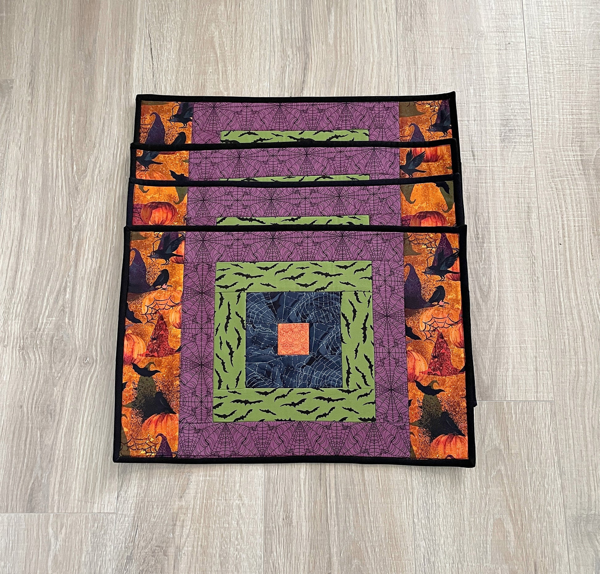 set of four quilted handmade placemats using Halloween fabric using a modern take on the courthouse steps quilt block.