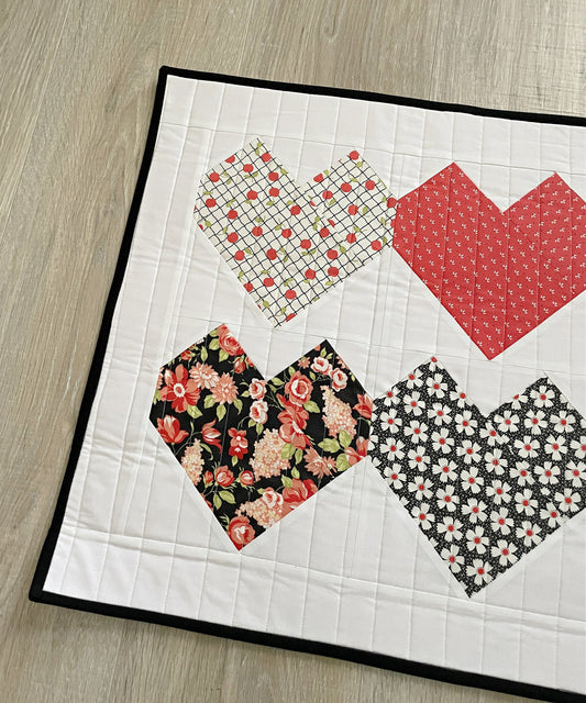 quilted table topper with red and black patchwork hearts