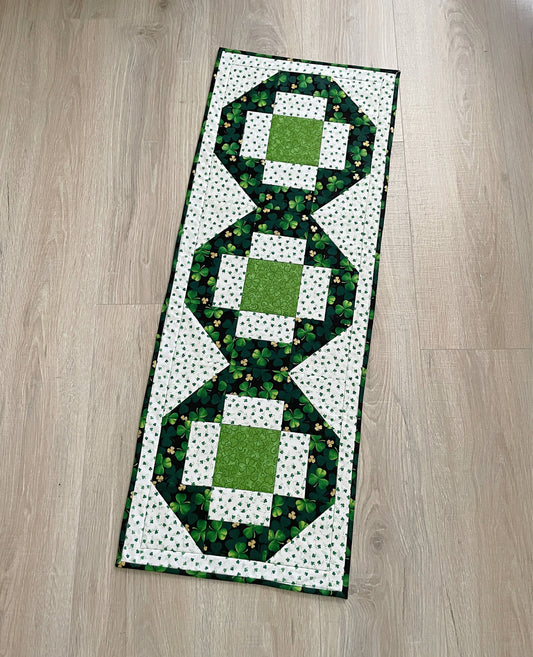 quilted table runner celebrating st. patricks day using green and white fabrics featuring clovers and shamrocks