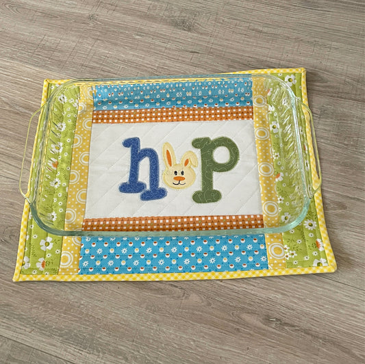 quilted casserole hot pad, yellow and blue with bunny embroidery in center panel spelling HOP