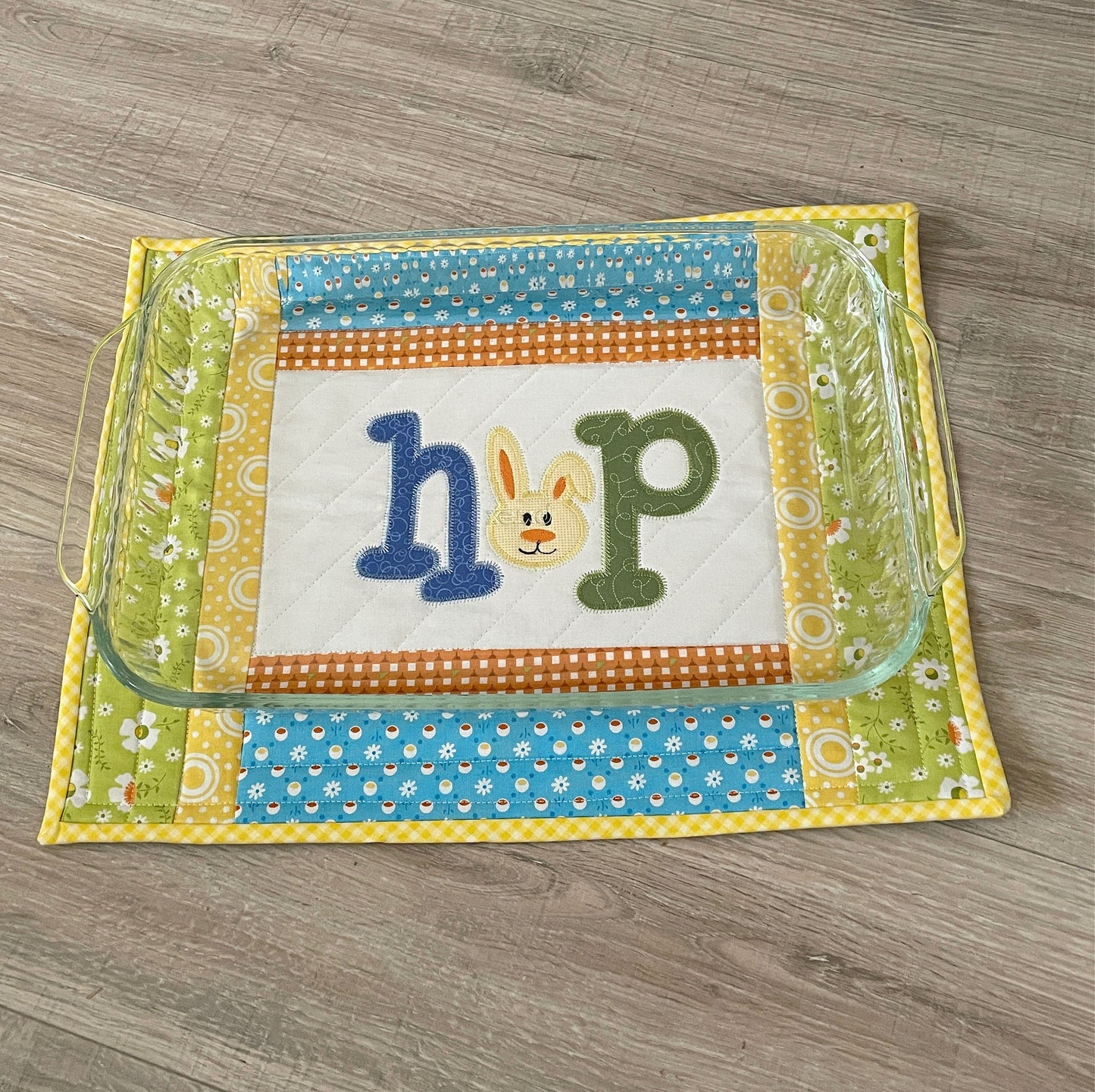 quilted casserole hot pad, yellow and blue with bunny embroidery in center panel spelling HOP